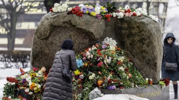 eine Frau legt Blumen bei einem ­Gedenkstein für die Opfer der Sowjetherrschaft in St. Petersburg nieder