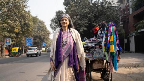 Portraitbild: Jayati Ghosh steht bei einem Verkaufsstand für Kleider neben einer Strasse