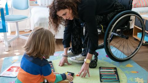 Elena Thut sitzt im Rollstuhl und spielt mit ihrem Sohn am Boden