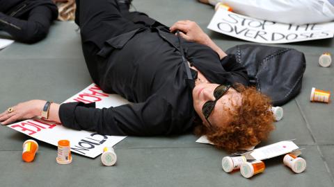 Nan Goldin im Film «All the Beauty and the Bloodshed»: sie liegt bei einer Demonstration am Boden und um sie sind leere Medikamenten-Dosen verstreut