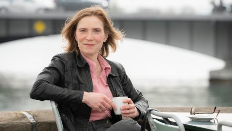 Judith Hofmann sitzt mit einem Kaffee in der Hand im Freien