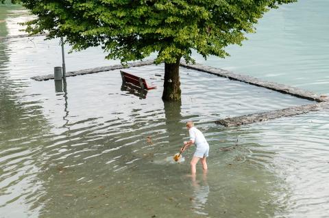 eine Person steht im Wasser des überschwemmten Ufers des Brienzersees