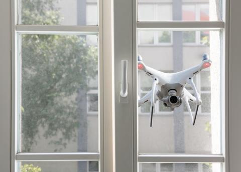 Symbolbild: Eine Drohne, die eine Wohnung ausspäht.