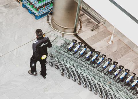 Arbeiter verschiebt Einkaufswagen im Shoppingcenter Letzipark
