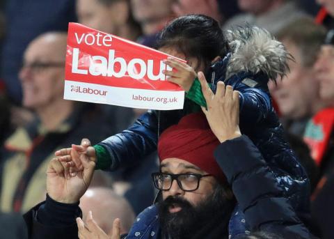 Vater mit Tochter, welche ein Labour-Plakat hochhält, an einem Match des FC Liverpool