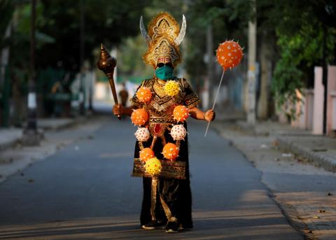 Person welche als Yama, Hindugott des Todes, verkleidet ist mit Corona-Dekoration