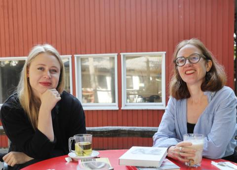 Katrin Sutter und Jil Erdmann sitzen beim Interview am Tisch und schauen den Fotografen an