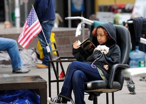 eine Frau liest während der OccupyWallStreet-Proteste im Oktober 2011 im Zuccotti Park ein Buch