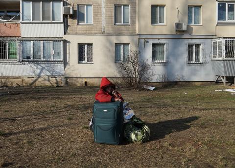 eine Frau mit Gepäck wartet am 14. März in Kiew darauf, dass sie abholt wird