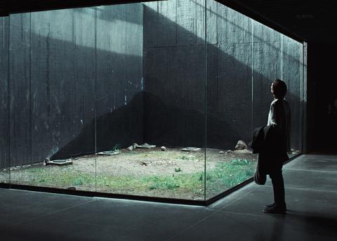 Filmstill aus «Memoria»: Eine Frau schaut durch Glaswände in einen Gebäude-Innenhof