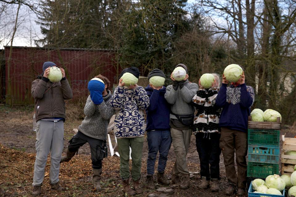 Aktivist:innen halten Kohlköpfe vor ihre Gesichter