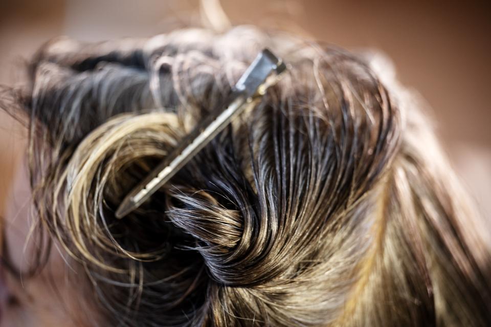 Haarklammer in den Haaren einer Person während dem Haareschneiden