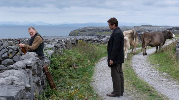 Filmstill aus «The Banshees of Inisherin»: Zwei Männer sprechen miteinander an einen Landweg, im Hintergrund sind 2 Kühe und das Meer zu sehen